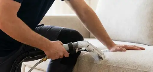 Professional upholstery cleaner deep-cleaning a fabric sofa with a handheld extraction tool, Honolulu, HI.